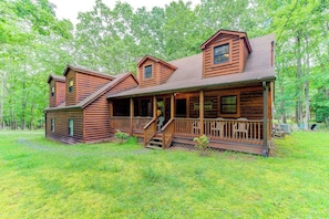 A log cabin with a porch, multiple windows, and a covered deck area.