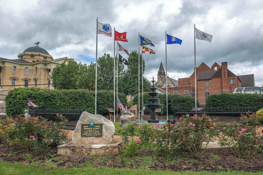 Un monumento con banderas, una fuente y un monumento de piedra.