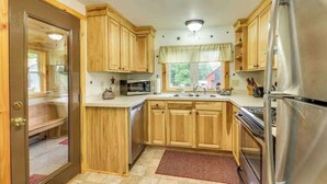 Eine Küche mit Holzausstattung, einem Edelstahlkühlschrank, einer Mikrowelle und einem Herd.