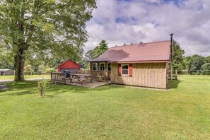 A wooden cabin with a red roof, a picnic table, and a small deck.