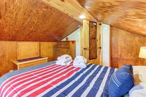 A wooden-paneled room with a bed, a small table, and a door.