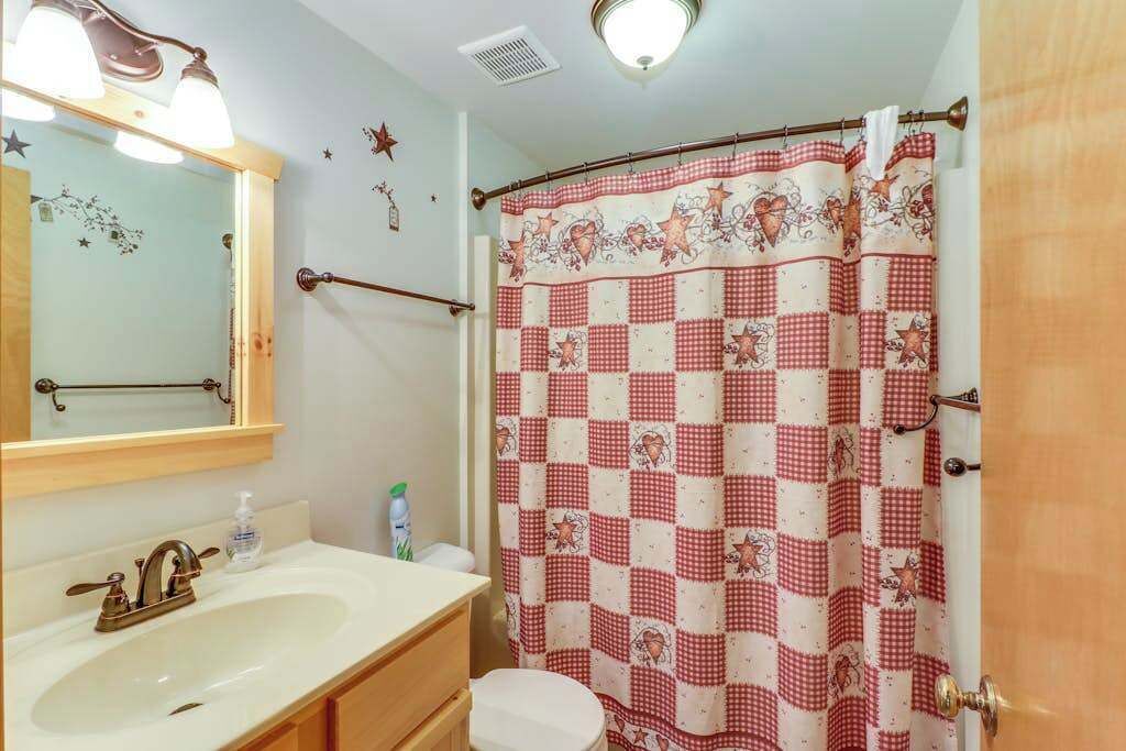 A bathroom with a sink, mirror, towel rack, and a shower curtain with a checkered pattern.