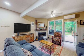 A living room with a television, sofa, fireplace, and a view through a glass door.