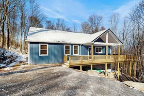 A two-story house with a wooden deck, a covered porch, and a garage. - Modern 4BR Cabin - Movie Theater - HOT TUB (McHenry)