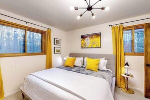 A bedroom with a bed, a bedside table, a lamp, and a painting on the wall.