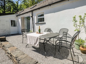 A patio with a table and chairs, a bottle of champagne, and a potted plant. - Daffodil Cottage (Treorchy)