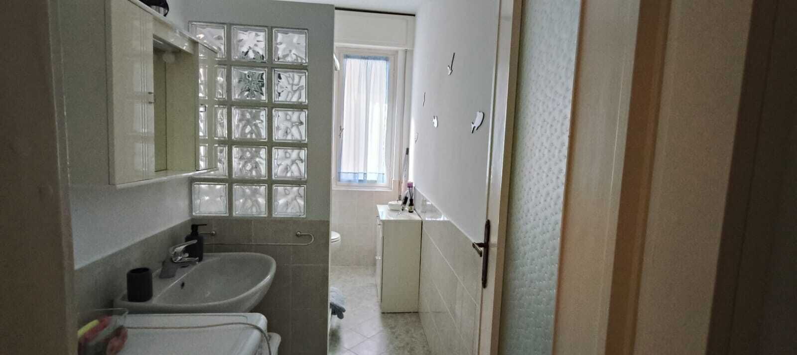 Une salle de bain avec un lavabo, un miroir et une fenêtre en verre dépoli.