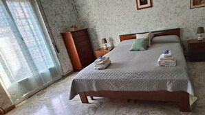 Quarto com cama, penteadeira, mesa de cabeceira e janela.