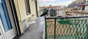 A balcony with a chair, a small table, and a bird on the railing. - Sanremo Note di Mare: Relax & Comfort Apartment, a 10-meter walk from downtown  (Sanremo)