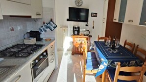 Cozinha compacta com fogão a gás, forno e mesa de jantar para quatro pessoas.