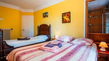 Une chambre d’hôtel avec deux lits, une tête de lit en bois, un radiateur et une fenêtre donnant sur un paysage agréable.