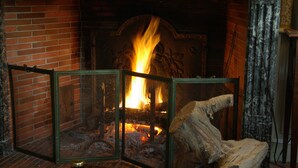 Ein Kamin mit brennendem Feuer, umgeben von einer Backsteinmauer und einem dekorativen Kaminvorsatz.