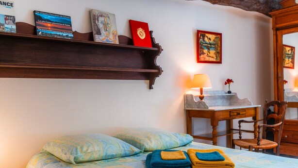 Ein Hotelzimmer mit einem Bett, einem Schreibtisch, einem Stuhl und einem Regal mit Büchern und einem Gemälde.