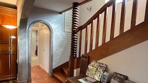Eine Treppe mit Holzbalkonen, einer Wandleuchte sowie einer Auswahl an Büchern und Zeitschriften.