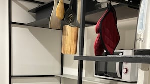 Eine Küche mit integriertem Mikrowellenherd, einer Spüle und hängenden Holzkochern.