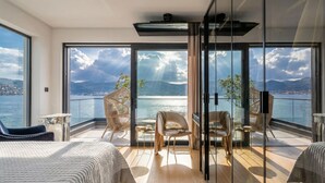 Ein Balkon mit Blick auf das Meer und die Berge, ausgestattet mit Stühlen und einem Tisch.