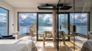 Ein Balkon mit Blick auf das Meer und die Berge, ausgestattet mit Stühlen und einem Tisch.