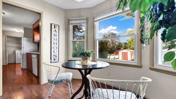 A corner kitchen with a dining table, chairs, and a view of the outdoors.