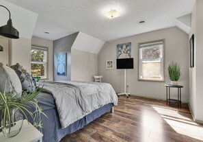 Une chambre à coucher avec un lit, une lampe sur pied, une plante en pot et une fenêtre.