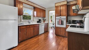 A kitchen with wooden cabinets, a refrigerator, a microwave, and a stove.