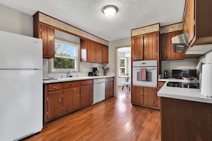 A kitchen with wooden cabinets, a refrigerator, a microwave, and a stove.