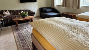 Une chambre d’hôtel avec un lit, un canapé, une chaise, une télévision, une fenêtre et une petite table.