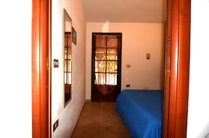 Ein Zimmer mit einem Bett, einer Tür mit Fenster und einem an der Wand montierten Lichtschalter.