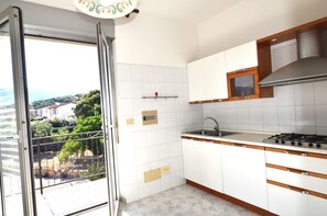A kitchen with white cabinets, a gas stove, and a window overlooking a garden. - Fst-jav01p1 in San Teodoro (San Teodoro)