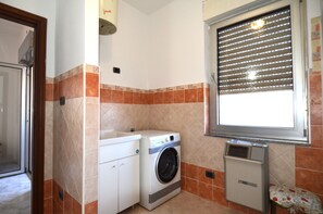 A laundry area with a washing machine, a dryer, and a window with blinds. - Fst-jav01p1 in San Teodoro (San Teodoro)