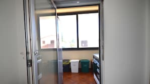 Eine Küche mit Fenster, Mülleimer und Kühlschrank.
