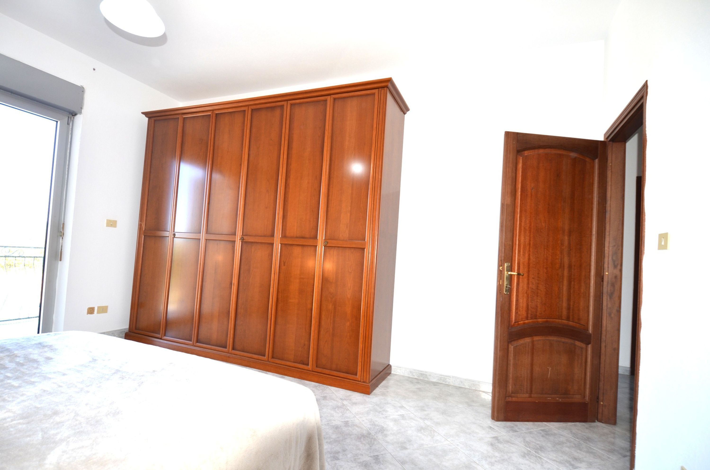 Une chambre avec une grande armoire, un lit et une porte.