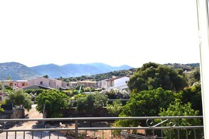 Ein Wohngebiet mit Häusern, Grünflächen und Bergen im Hintergrund.