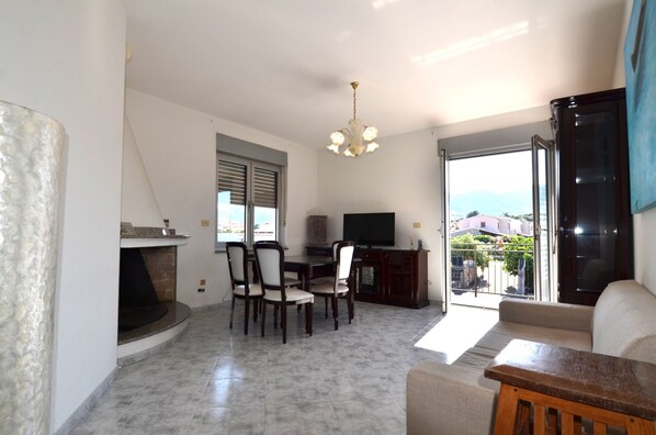 Sala de estar con chimenea, comedor, televisor y vistas a través de un ventanal.