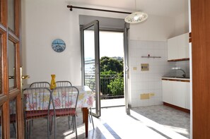 Un comedor con una mesa y sillas, un reloj en la pared y vistas al exterior a través de una puerta abierta.