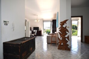 Amplia sala de estar con mesa de billar, una escultura de madera y vistas a través de un ventanal.