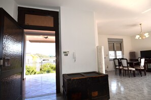 Una sala de estar con comedor, un cofre de madera grande, una araña y vistas al exterior.