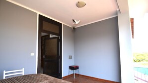 A room with a wooden table, a chair, a door, a small stool, and a balcony with a railing. - Fst-jav01p1 in San Teodoro (San Teodoro)