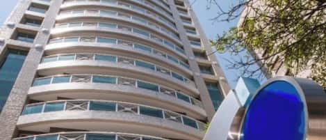 A high-rise building with a curved facade, multiple balconies, and a prominent blue circular feature.