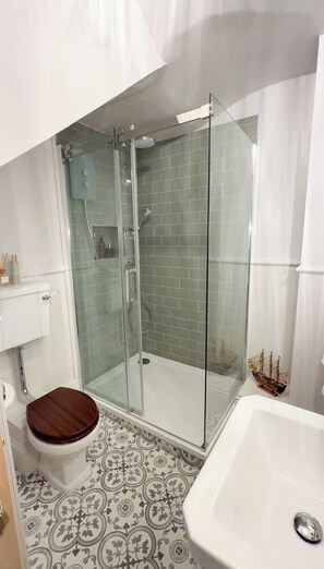 A bathroom with a glass-enclosed shower, a toilet with a wooden seat, and a white bathtub. - Romantic Georgian Apartment - Prime Location (Royal Tunbridge Wells)