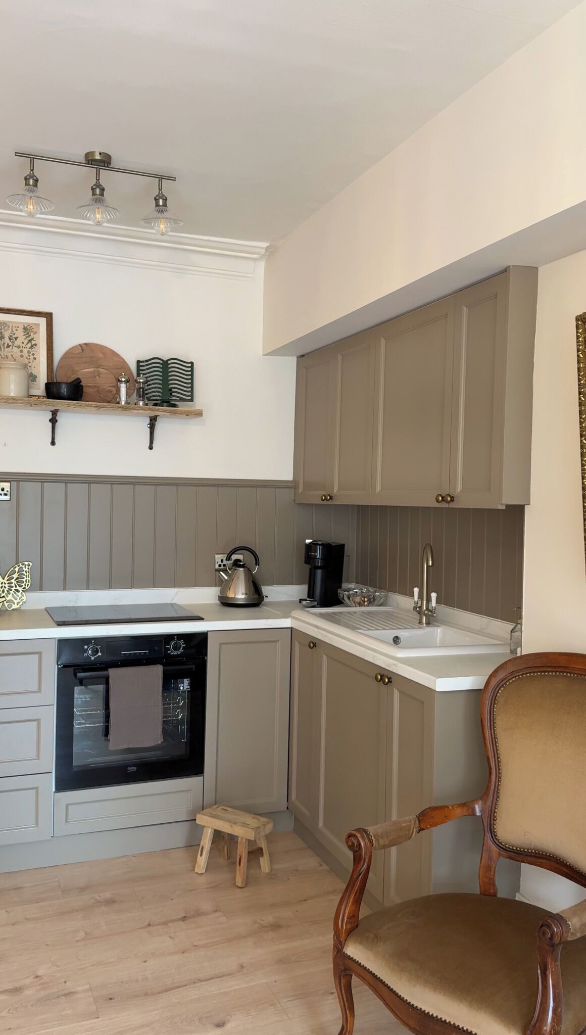 A kitchen with a built-in oven, a coffee maker, and a small stool.