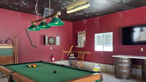 A pool table with balls, a dartboard, a television, and a bar area with a barrel. - South Baptiste Lake View | Boat Launch | Game Room (Hastings Highlands)