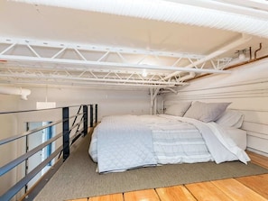 A bedroom with a bed, a window, and a balcony railing. - Modern Loft Haven | BBQ, Sleeps 6 | (Calgary)