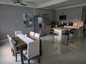 A modern kitchen with a central island, bar stools, and a dining table with chairs. - 2 Bedroom Villa, Private Beach, Communal Pool & Gym (Saint Ann's Bay)