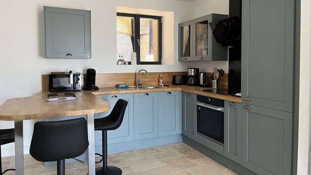 A modern kitchen with grey cabinets, a wooden countertop, a built-in oven, and a window above the sink. - Farm cottage (Le Haut-Corlay)