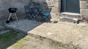 A stone house with a chimney, a sliding glass door, and a barbecue grill. - Farm cottage (Le Haut-Corlay)