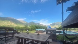 Een terras met picknicktafels, een barbecue en een zwembad.
