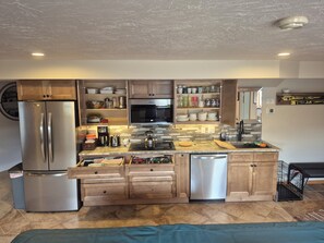 Una cocina moderna con electrodomésticos de acero inoxidable, armarios de madera y salpicadero de azulejos.