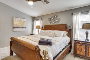 A bedroom with a large bed, a nightstand, a dresser, a wall art piece, and a window with curtains. - Maricopa Pet-Friendly w/Private Pool & Hot Tub (Maricopa)