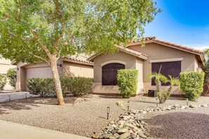 A residential house with a garage, a tree, and a gravel driveway. - Maricopa Pet-Friendly w/Private Pool & Hot Tub (Maricopa)