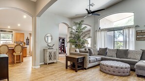 Ein geräumiges Wohnzimmer mit einer großen Couch, einem Couchtisch und einem Deckenventilator.
